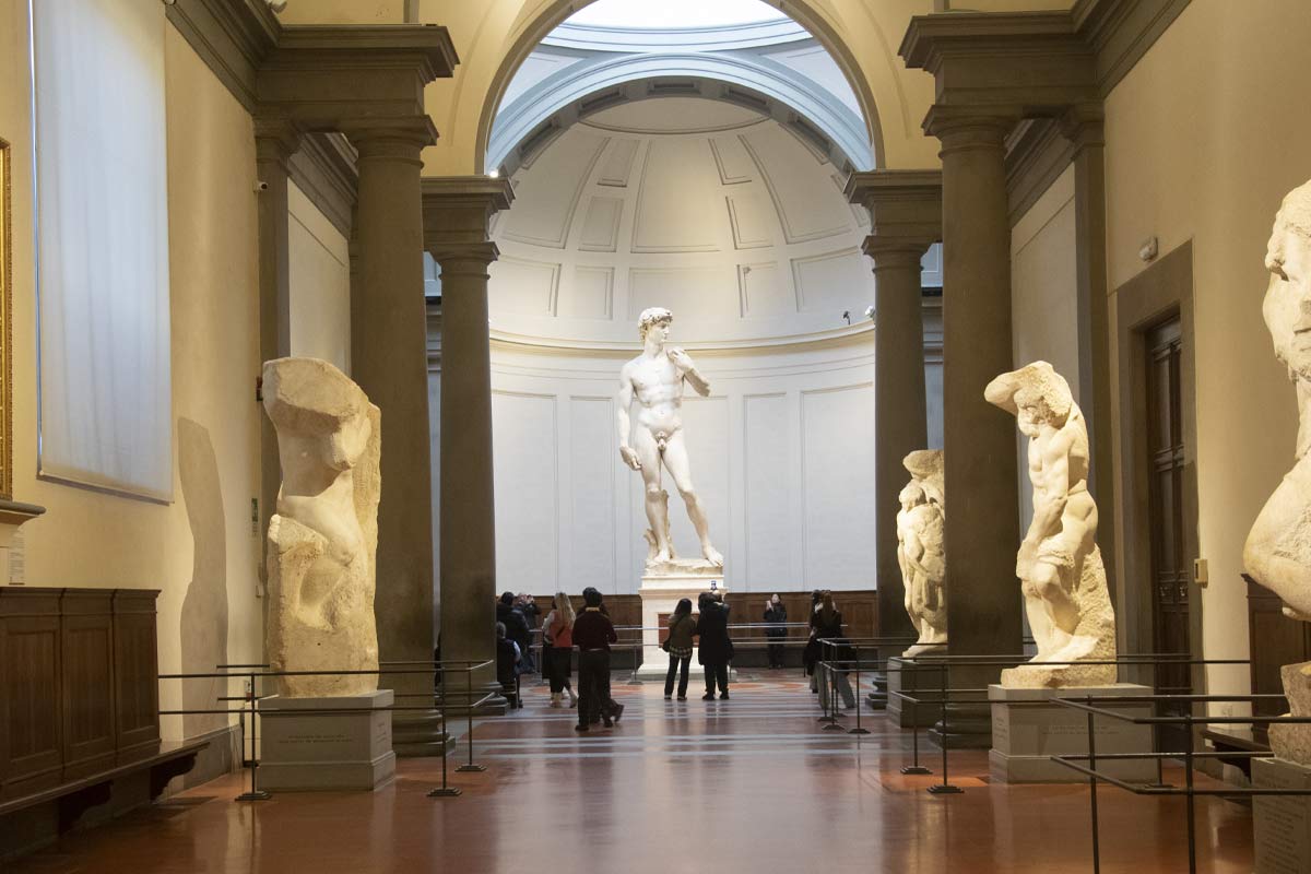 David displayed in Tribune Hall at Accademia Gallery with dramatic lighting and crowds