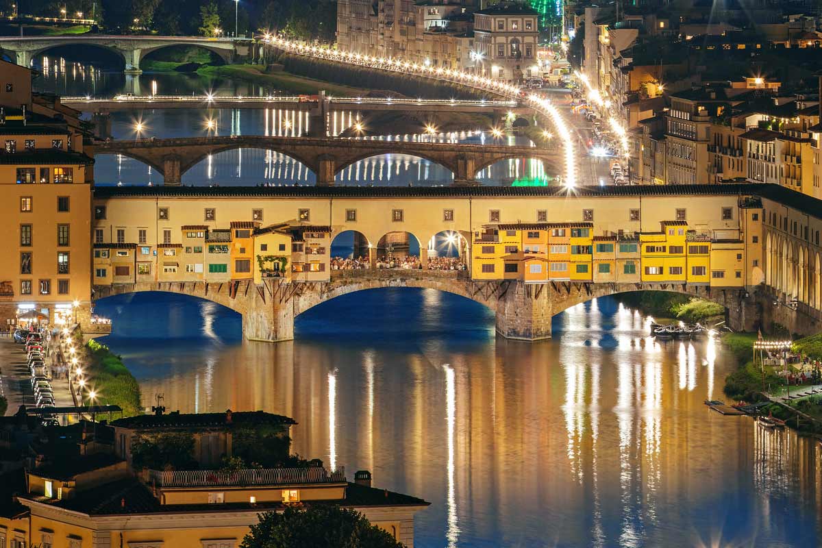Ponte Vecchio illuminated at night reflecting in Arno River romantic Florence evening